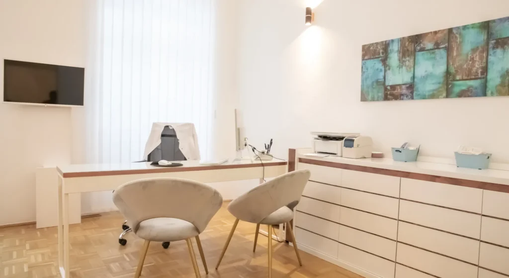 Behandlungsraum mit Schreibtisch und Sitzgelegenheiten